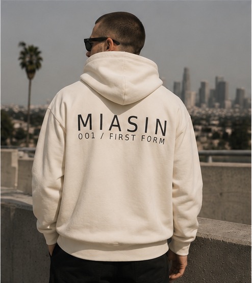 A model photographed from behind wearing the bone MIASIN 001 hoodie above the Los Angeles skyline
